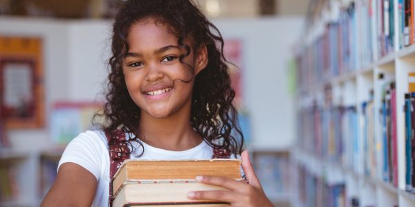 portrait-of-smiling-african-american-schoolgirl-carrying-stack-of-books-in-school-library.jpg portrait-of-smiling-african-american-schoolgirl-carrying-stack-of-books-in-school-library.jpg